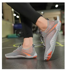 Nahaufnahme grauer Barfußschuhe mit orangen Details und Schnellverschluss im Fitnessstudio