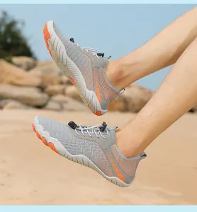 Outdoor-Wasserschuhe mit grauem Mesh und oranger rutschfester Gummisohle auf Strandfelsen