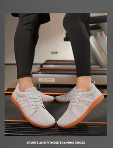 Photo de chaussures d'entraînement pieds nus grises avec semelles orange sur tapis