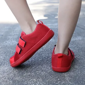 Kids red wide-toe barefoot sneakers with mesh upper and velcro straps on outdoor ground