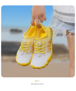 Detail von gelben Kinder-Wasserschuhen mit atmungsaktivem Netz und Schnellverschluss am Strand