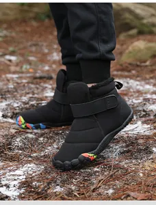 Detail of waterproof black snow boots with hook-and-loop closure on forest ground