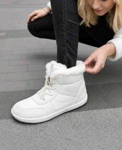 Detail of warm off-white snow boots featuring thick white faux fur lining and lace-up toggle