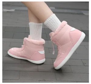 Close-up of pink waterproof snow boots with faux fur collar and warm lining on stone pavement