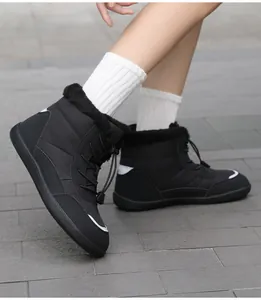 Side view of black waterproof snow boots with faux fur lining on an outdoor pavement