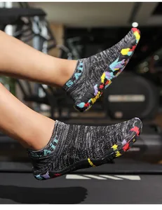 Dettaglio scarpa a piedi nudi in maglia grigia con scritta SAIL e suola in gomma colorata