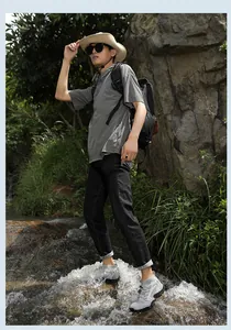 Primer plano de zapatos de senderismo grises transpirables sobre rocas de un río