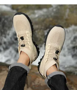 Primer plano de zapatillas de senderismo beige de malla con cordón en rocas de río