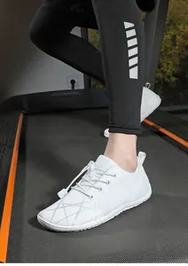 Detail of white barefoot running shoes with breathable mesh and quick lace toggle on treadmill