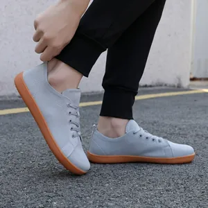 Gray knit barefoot walking shoe with gum sole shown on asphalt outdoors for active lifestyle