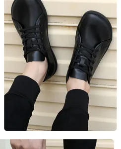 Draufsicht auf schwarze Barfußschuhe mit breiter Zehenbox und matten Oberflächen auf Gelb