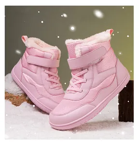 Detailed view of pink children's winter boots with warm plush lining on snow-like surface