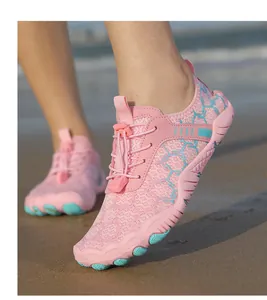 Chaussures d'eau roses et bleues avec motifs nid d'abeille sur une plage de sable