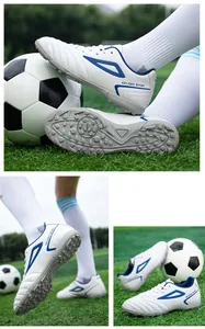 Detail of white soccer cleats with blue logo and non-slip turf sole for training