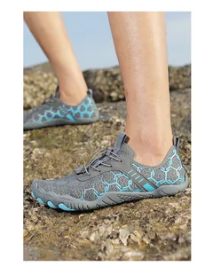 Détail de chaussures aquatiques gris et bleu avec semelle antidérapante sur rochers