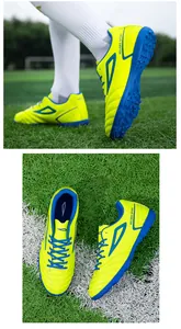 Detail view of fluorescent yellow turf football boots with blue laces on green grass