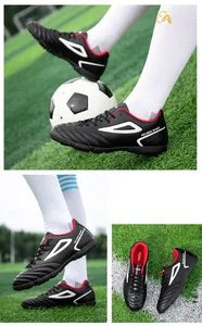 Close-up of turf soccer cleats with textured upper and white geometric patterns on the side