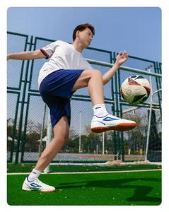 Toma de acción de zapatillas de fútbol blancas para hombre sobre césped artificial
