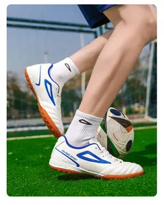 Primer plano de zapatillas de fútbol con tacos de goma sobre césped artificial