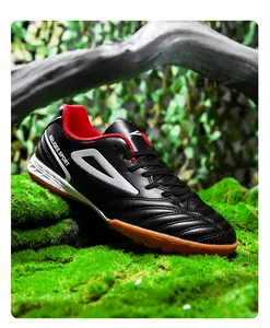Detalle de botas de fútbol turf negro y rojo con suela de goma antideslizante