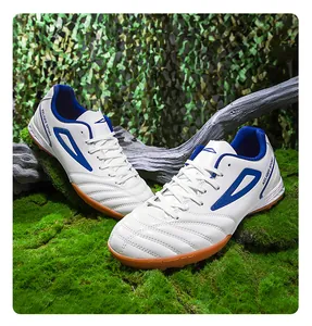 Primer plano de botas de fútbol blancas y azules con tacos TF sobre césped y musgo
