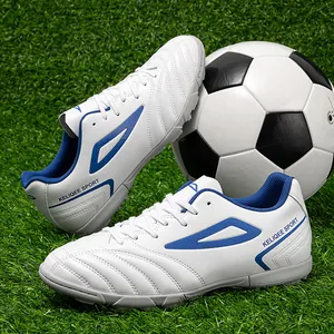 White low-top turf soccer shoes with blue accents on green artificial grass field