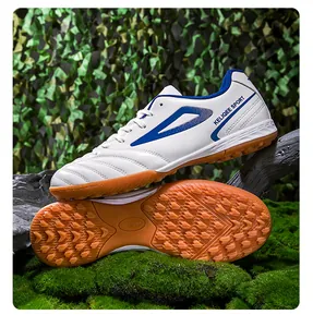 Detalle de zapatos de fútbol blancos con tacos turf y patrones geométricos azules hombre