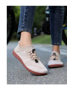 Detail of beige breathable knit walking shoe with bungee laces on outdoor path