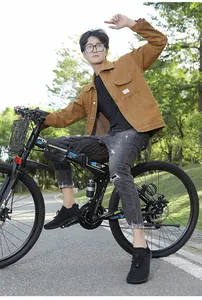 Man in brown canvas jacket and grey jeans riding a bike on an outdoor park path