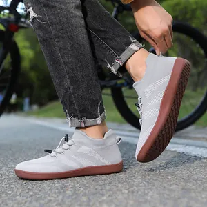 Grey knit breathable sneakers with rubber soles and bungee laces on an asphalt road