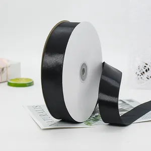 Elegant black satin ribbon roll on a marble gift box with fresh decorative accents