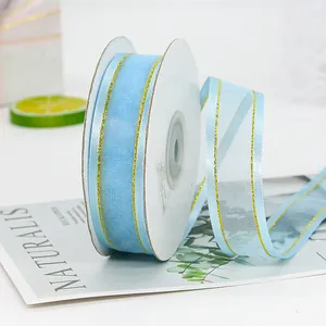 Light blue organza ribbon with gold metallic edges on a spool for gift wrapping