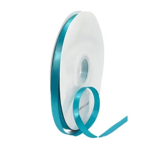 Single roll of peacock blue polyester satin ribbon on white spool for gift wrapping