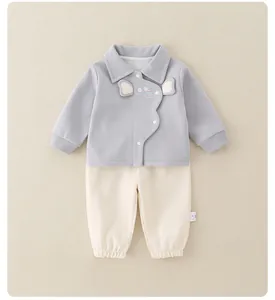 Detail view of baby cotton set featuring a grey jacket with mouse embroidery and cream pants