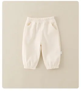 Detail view of cream cotton jogger pants with elastic waistband and ribbed cuffs for kids