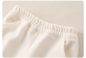Detail of elastic waistband and soft cotton fabric on cream casual pants for kids
