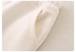 Detail of cream cotton kids sweatpants showing elastic waistband and side pocket stitching