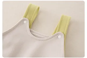 Detailaufnahme von Baby-Oberteil mit gelbgrünen Trägern und weißen Druckknöpfen