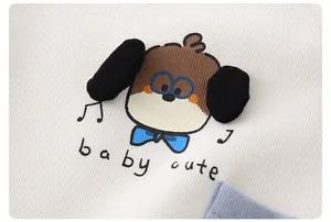 Detail des Baby-Oberteils aus Baumwolle mit Welpenstickerei und blauer Tasche