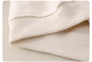 Dettaglio dell'orlo a coste e delle cuciture sul maglione in maglia di cotone crema