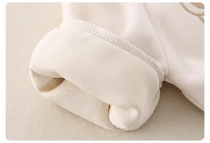 Dettaglio del set in cotone per neonati con fodera in pile e ricamo su tessuto crema