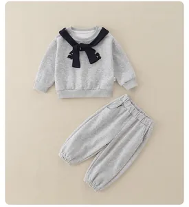 Detailed flat lay of children's grey knit sweatshirt and joggers set with blue bow neck tie