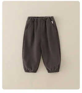 Detail of dark brown kids jogger pants with elastic waistband and woven logo patch