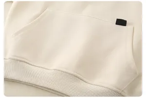 Detail of children's beige hoodie showing kangaroo pocket and ribbed hem texture