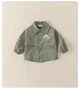 Détail de la veste enfant vert gris avec étiquette taille 90, boutons et logo poitrine