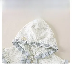 Macro detail of baby floral hoodie with lace trim, blue bow, and cute bear zipper pull