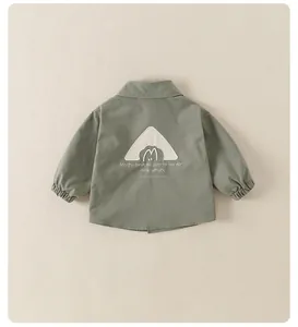 Détail du dos d'une veste enfant vert gris avec broderie et texte festif de fête