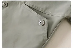 Détail d'une veste enfant vert gris montrant les coutures de poche et boutons