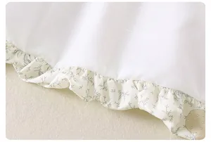 Close-up of ruffled hem with green floral prints on white girls cotton jacket