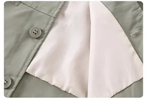 Détail macro d'une veste vert olive avec double surpiqûre et boutons en résine